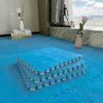 Блакитний килимок-пазл: стопка плит 30×30 на зібраному пухнастому покритті біля вікна